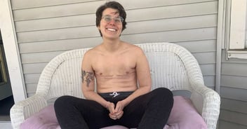 Evvie sits bare-chested and smiles happily